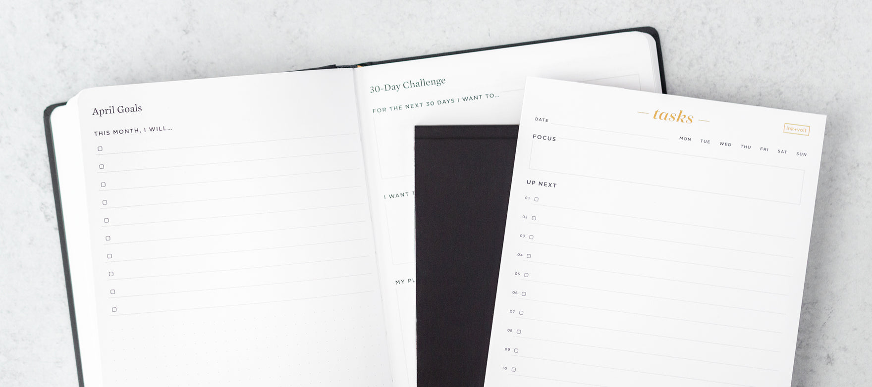A planner is open to a 30 day challenge page, with a small stack of notepads on top.
