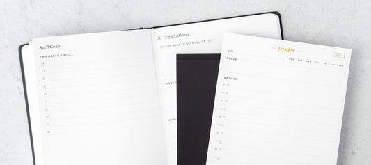 A planner is open to a 30 day challenge page, with a small stack of notepads on top.