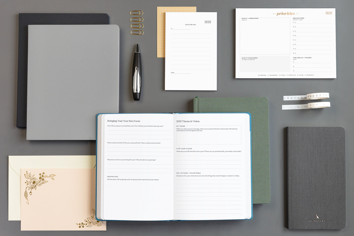 A busy array of productivity tools to help with work-life balance - notepads, notebooks, a planner, pens, washi tape, and stationery.