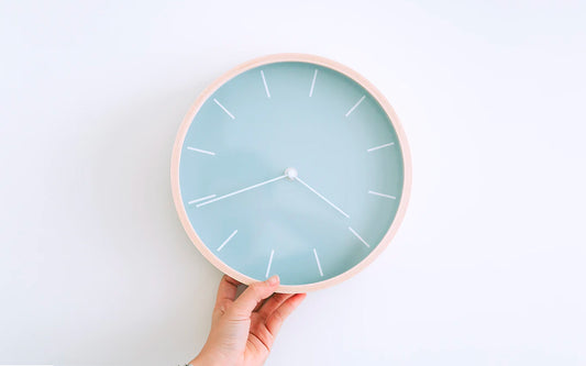 A blue clock against a white wall