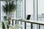 A desktop on a tall desk in front of a wall of windows