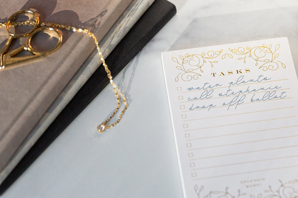 A notepad next to a book and a gold chain