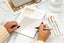 two hands write on a running list notepad