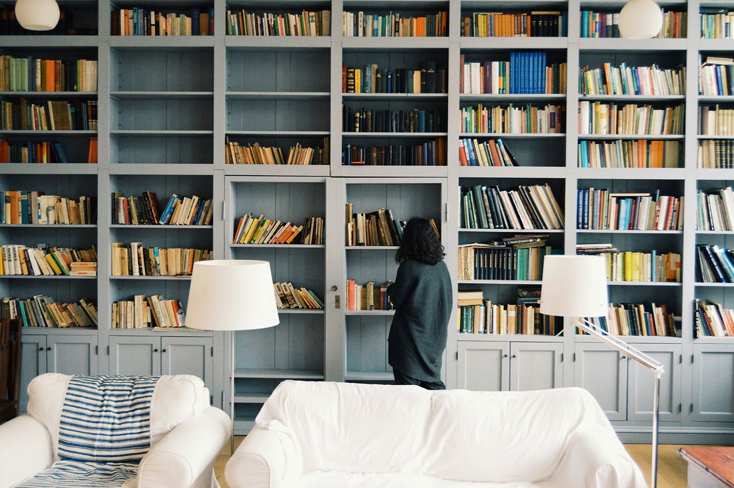 A woman stands in front of a wall of bookcases filled with books