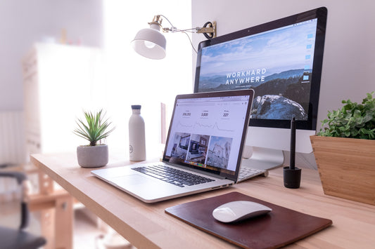 A laptop and desktop computer on a clean wooden desk