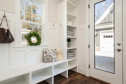A clean and tidy entryway to a home with wood floors and white shelves
