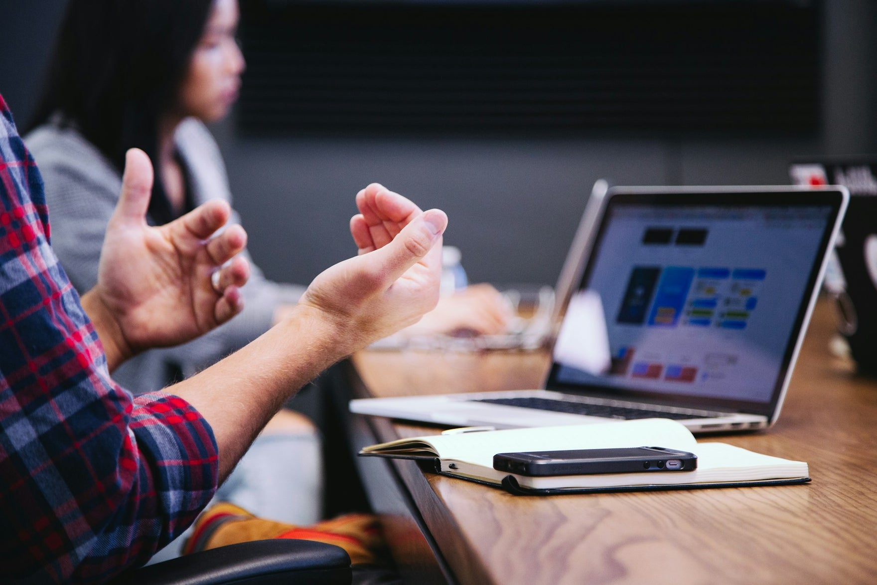 A person's hands gesturing in front of a computer on a table