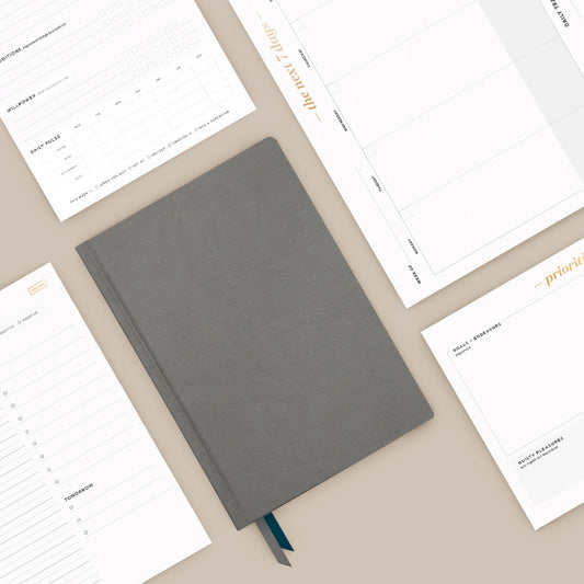 A stack of productivity notepads on a grey marble tabletop