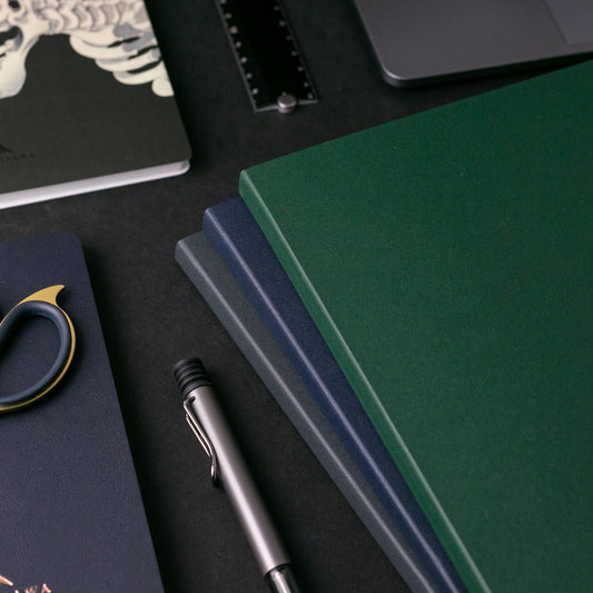 Executive notebooks on a black table with other desk accessories