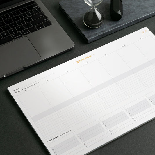 An organized desk with dark accessories and a white notepad