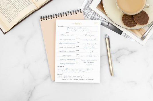 Two notepads and a gold pen on a marble countertop