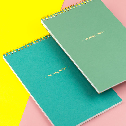 Two meeting notes notepads in front of a colorful background