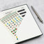 A planner opened to a folder page with stickers and weekly tabs