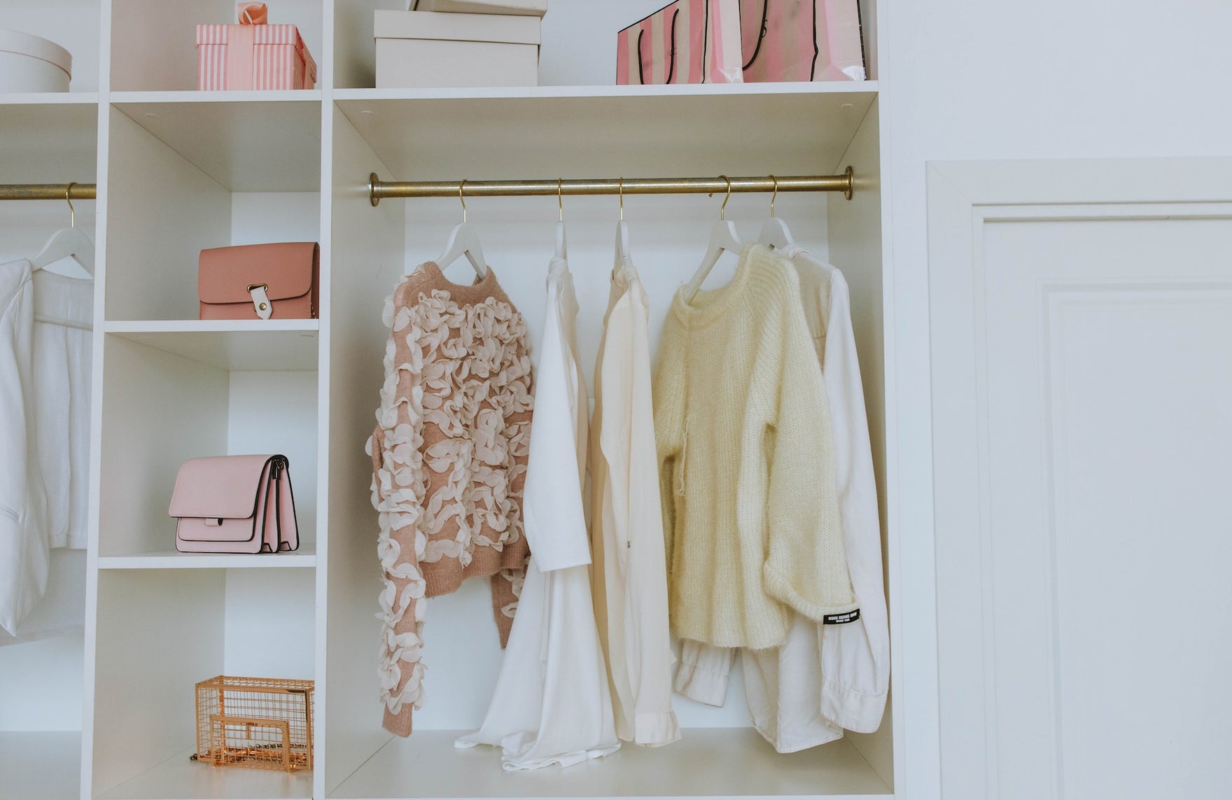 A minimalist closet with white and pink clothes and details