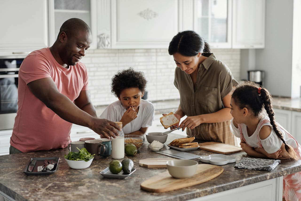 A family stands around a kitchen island working on food together