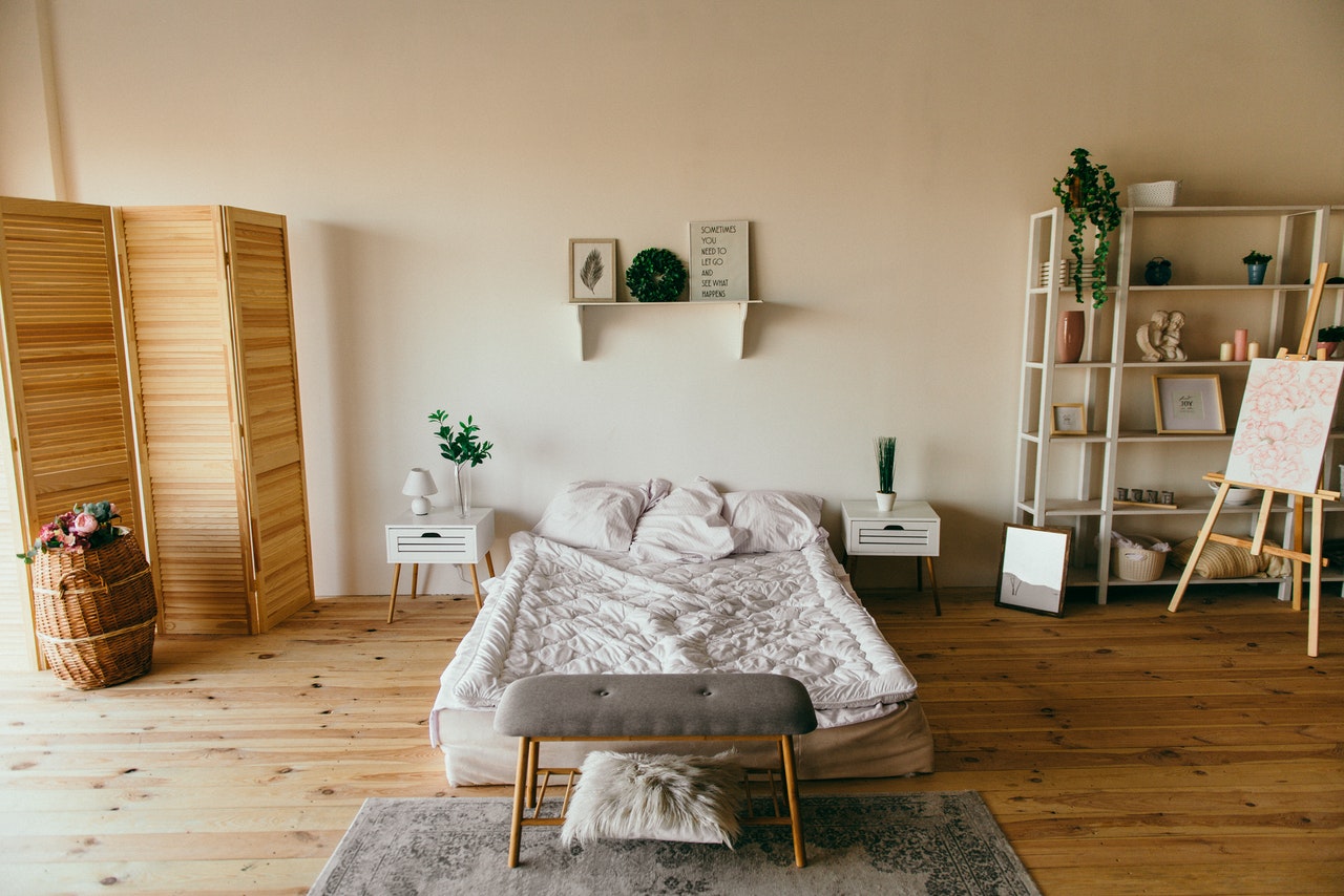 A tidy bedroom with a white bed and wood accents, example of how to clean your room.