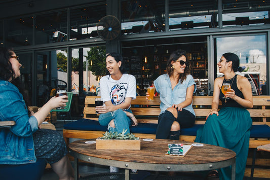 A group of women sit around an outdoor table with drinks