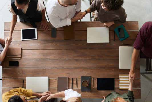 A top view look at a team of working people around a wood table