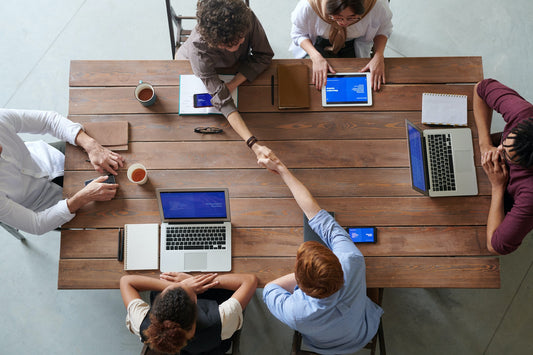 Six people sitting around a conference table with two people shaking hands across the table