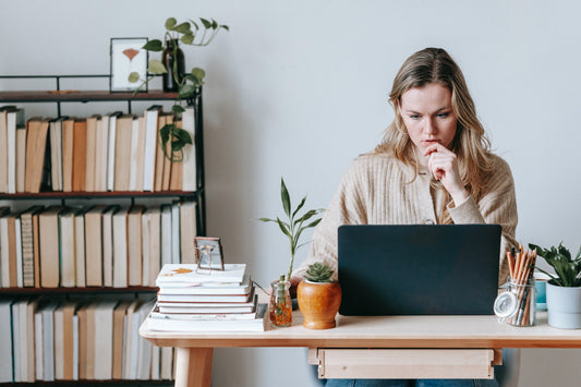 A woman sits at a desk with an organized bookshelf behind her