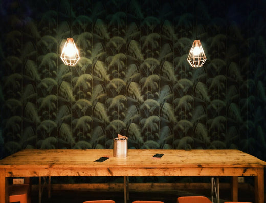 A wood table in front of green and black wallpaper