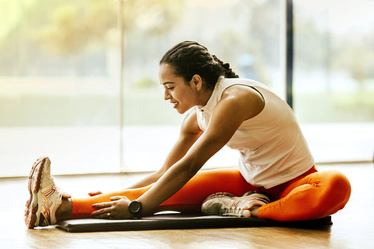 A woman stretches on a yoga mat in front of a window