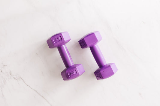 Two purple hand weights on a white floor.