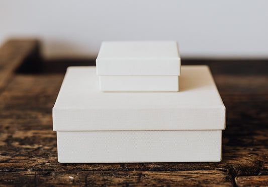 Two white boxes stacked on a dark brown wood tabletop