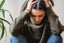 A woman looks down, holding her head, looking stressed