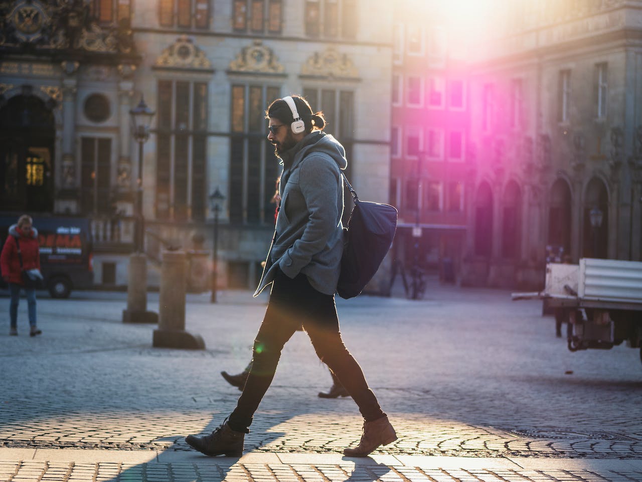 A man wearing headphones walks down a city street