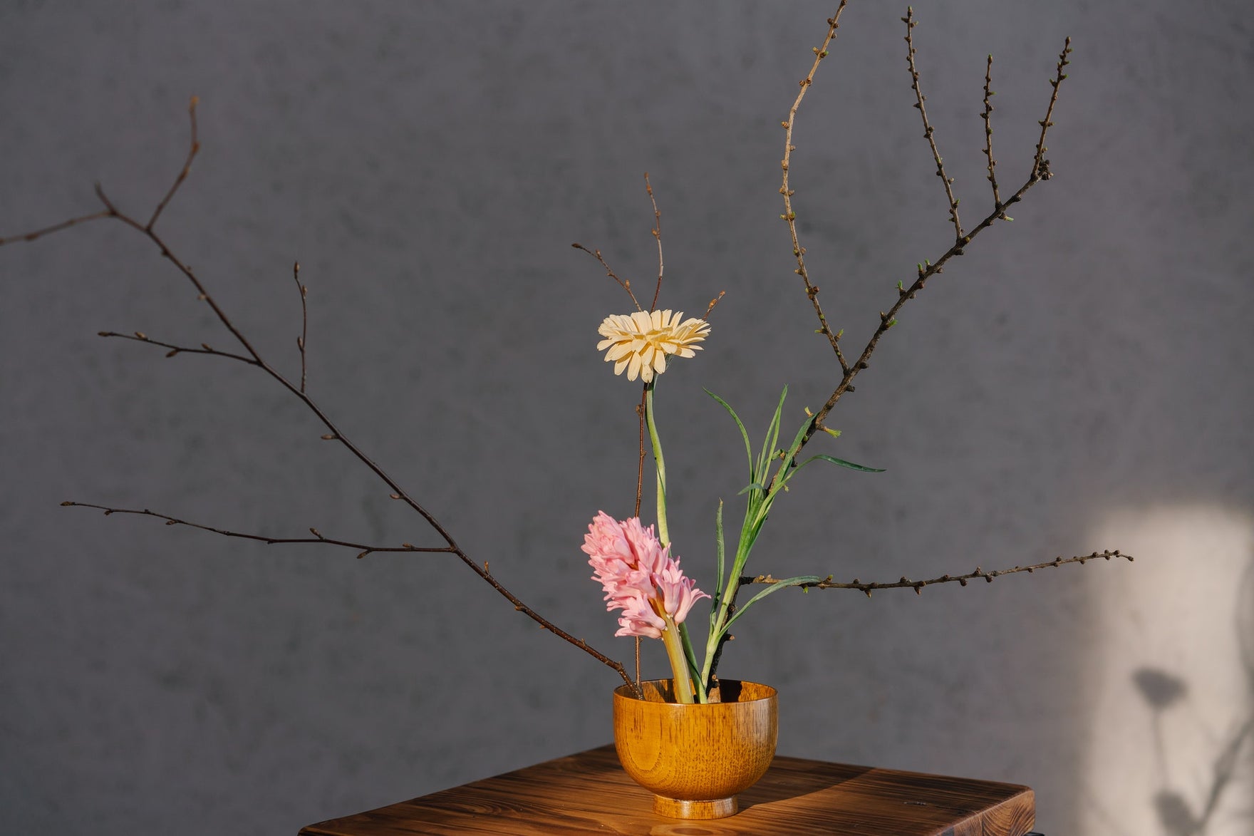 a delicate bouquet of two flowers and several thin branches in a terra cotta pot