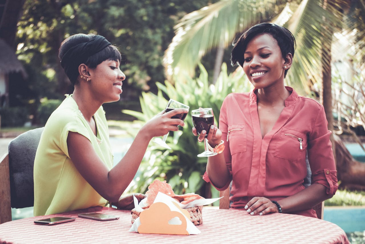 Two women sit at an outside table smiling