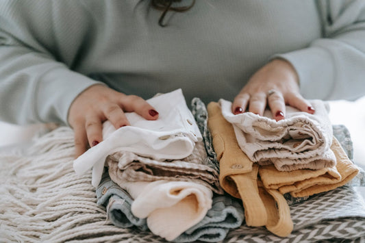 A woman's hands rest on two stacks of clean folded laundry