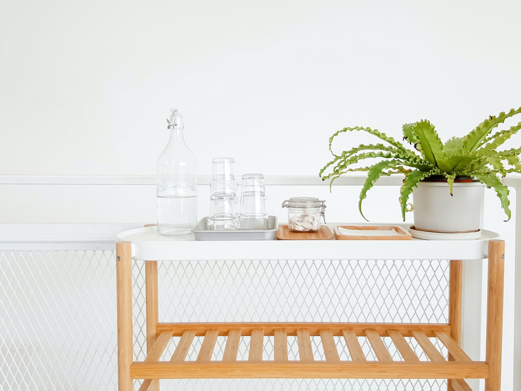 A white bathroom countertop with glass jars and a small green plant in a white pot