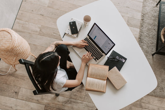 A view from above of woman working at a desk with a computer and books.