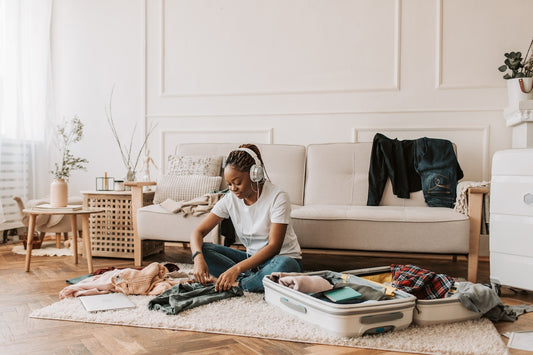 A woman folds clothes to pack into a suitcase in a bright living room