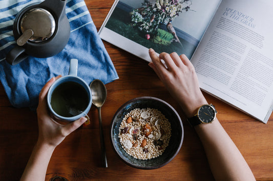 Person holding coffee cup and flipping through magazine