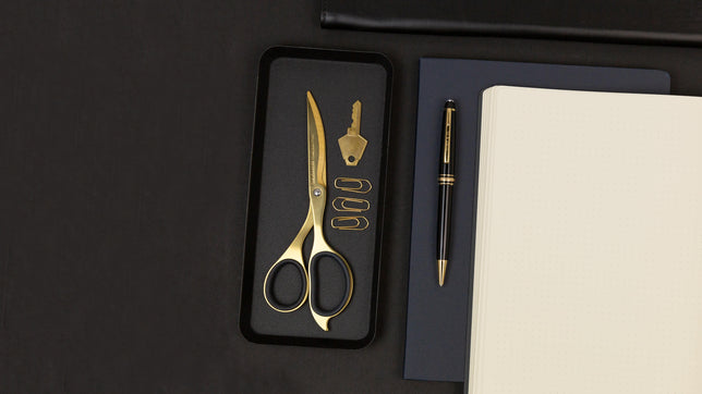 gold scissors and paper clips on a black backdrop