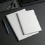 Two spiral-bound notebooks on a dark surface with pens.