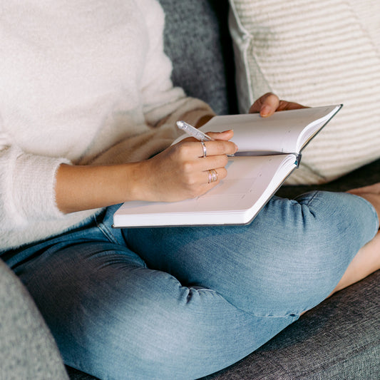 woman sitting on couch writing in a planner