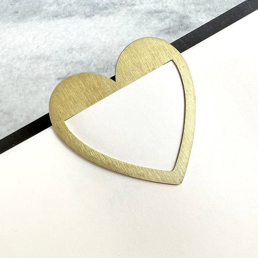 heart shaped brass page marker shown on a page in a notebook