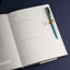 Open notebook with a blue pen on a dark background