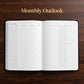 An open monthly outlook planner on a dark wood background, with the text 'Monthly Outlook' written above it. The pages are white with a minimalist grid layout for January 2027.
