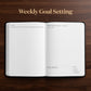 An open weekly goal-setting planner or notebook lies on a dark wood background, with the words 'Weekly Goal Setting' printed above it. The pages are white with black text and lined sections for goal tracking.