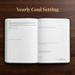An open yearly goal setting planner or notebook lies flat on a dark wood background, with the title 'Yearly Goal Setting' printed above it. The pages are white with black text and lined sections for goals, action plan, notes, and processes.