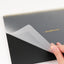 Hand holding a clear screen protector over a notebook with 'dashboard' branding.