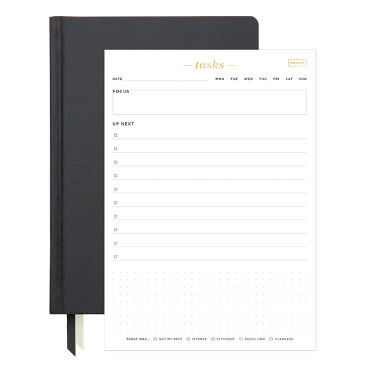 Black planner with a white task list page on a white background