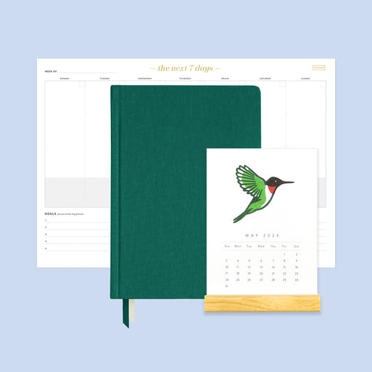 Green planner with a stand and calendar on a light blue background